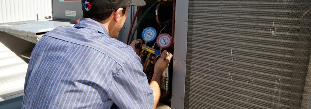 HVAC technician servicing a condenser unit in Walton