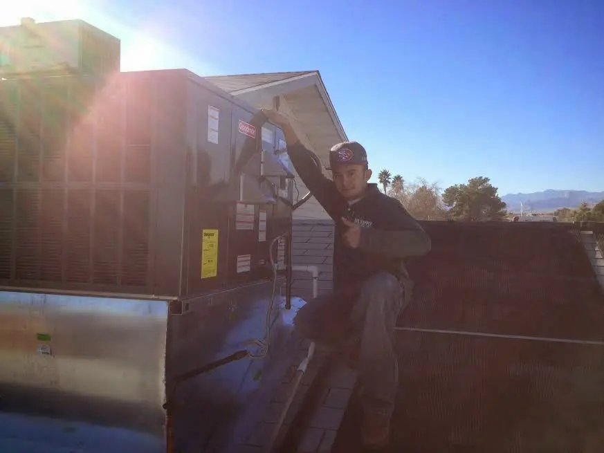 HVAC technician performing AC Tune-Up on a rooftop unit in Walton